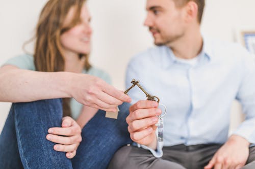 Free Man and Woman Sitting while Holding Keys Stock Photo